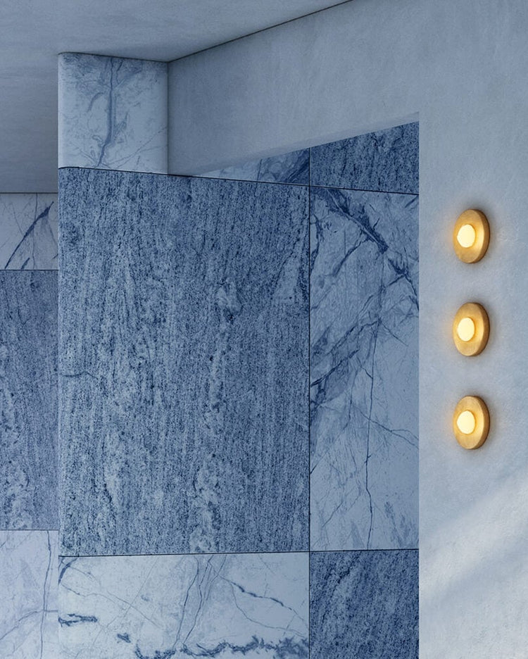 Round brass sconces against a blue marble wall