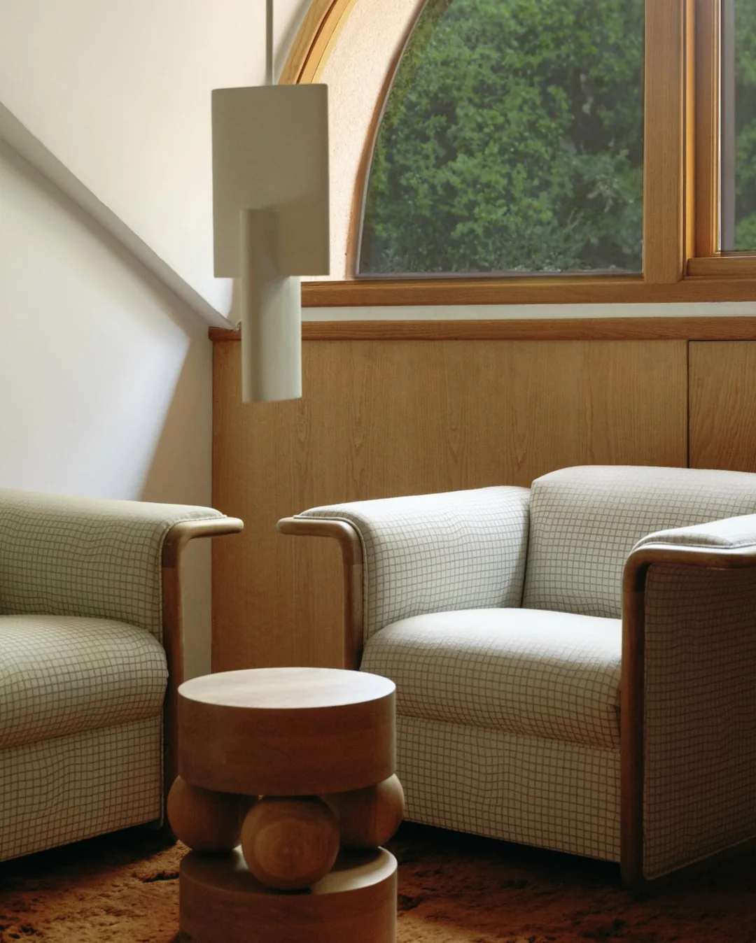 White Lotura pendant above checkered armchairs